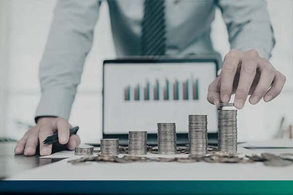 Financial table presented in a laptop and a pile of coins in front of it